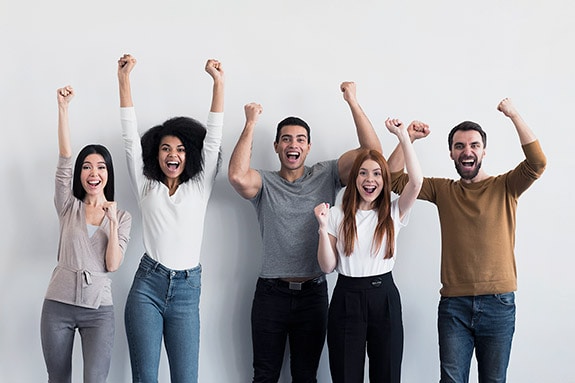 A group of diverse people celebrating with raised hands, expressing joy and unity.